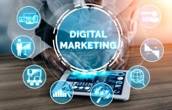A digital marketing image featuring a tablet surrounded by icons representing marketing tools and strategies like social media, email, data analytics, and global reach. It symbolizes the multi-channel nature of digital marketing