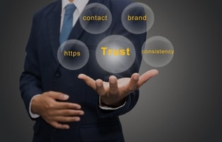 A professional holding bubbles labeled with trust-building elements like contact, brand, consistency, and HTTPS—emphasizing digital credibility