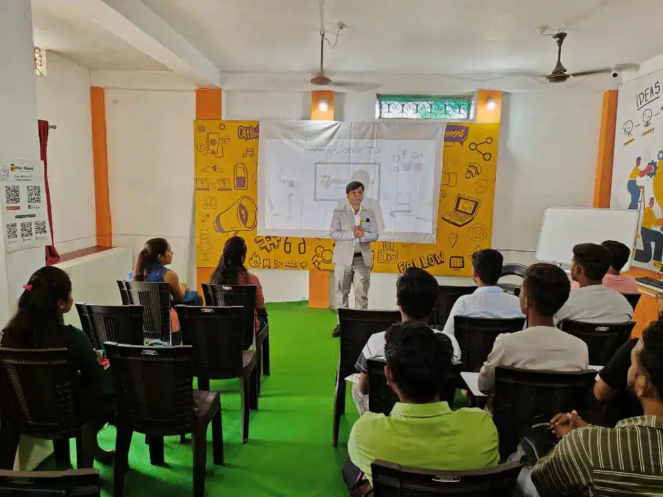 A speaker presenting a digital marketing slideshow to an attentive audience in a classroom at a Niksh Digital training center.